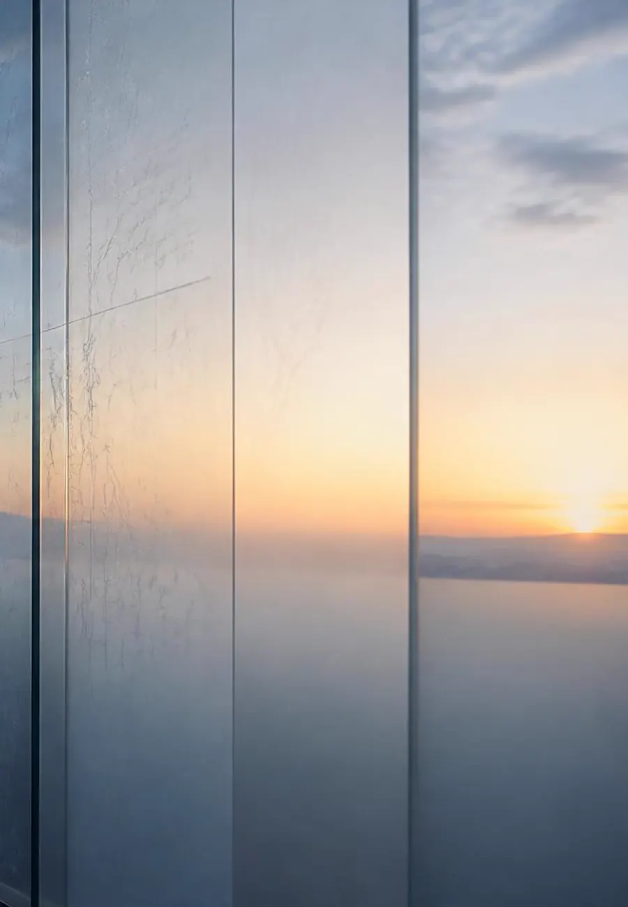 Frosted glass panels opening onto a sunrise over the water